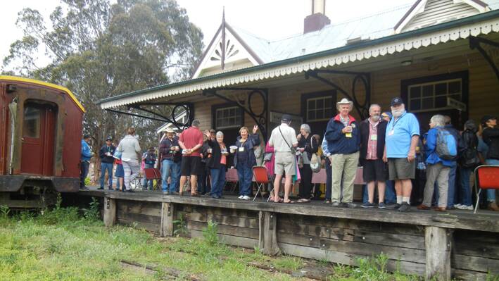 Many of the Dodge Bros Car Rally participants enjoying morning tea supplied by the members of the Grenfell Lions Club and sheltering from the rain on the platform at the Railway Station on Monday morning. 