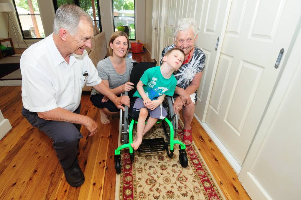 Myles Wilton moves around his home in his new wheelchair to the delight of Pat Yeo, mother Ali Wilton and Barb Kelly.									      									        Photo: LOUISE DONGES