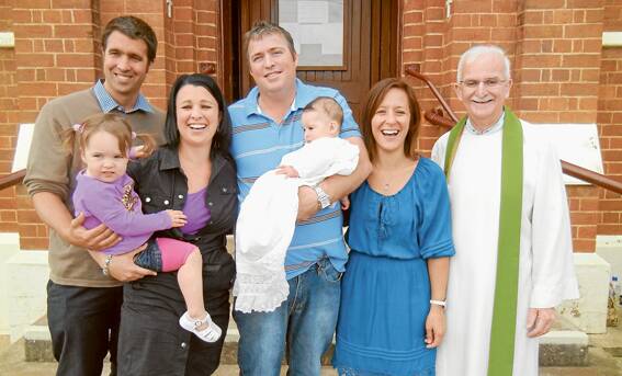 Pictured on the steps of St Joseph’s Church following Maisie Jane Baker’s Baptism are (L-R)  Godparents Edward and Vanessa Dunstan - Vanessa is holding Maisie’s big sister Nellie, Dean holding Maisie, and Phoebe Baker with Father Allen Crowe.
