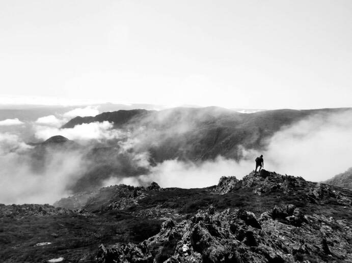 A man climbs Mount Kosciuszko with fog looming above the mountain tops, taken by a teen-aged Brenton Cox with a black and white filter. Picture by Brenton Cox.