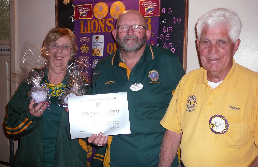 President Lion Terry Carroll presenting an appreciation certificate and gift to Second VDG Lion Ron Parry and his wife Lion Barbara.