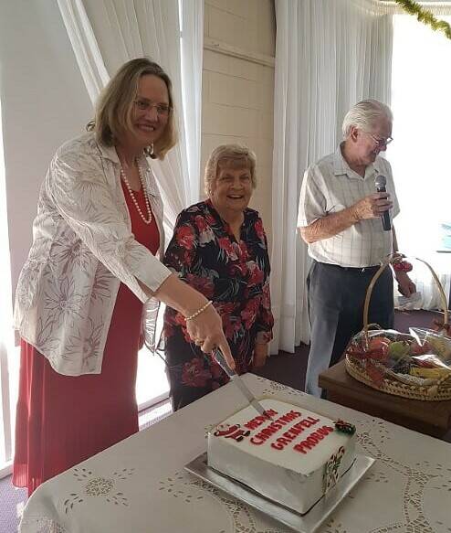 Annette Katona and Dot Fitzpatrick cutting the Probus Club Christmas Cake, with emcee Brian McDonald. Photo by Gwen Clark.