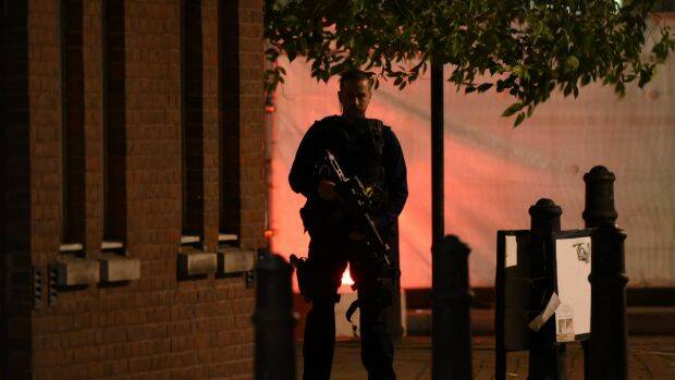 An armed police officer stands guard on a corner near London Bridge.  Photo: Carl Court