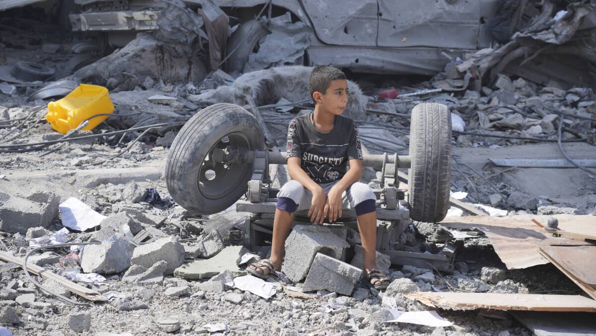 A Palestinian boy sits on the rubble of his building destroyed in an Israeli airstrike. Picture AP 
