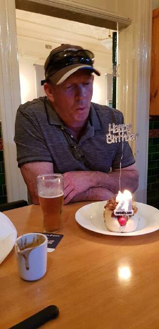 Andy Stevens blowing out the candle on his birthday treat - a Railway Hotel Hotdog. Cont