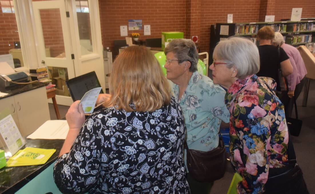 Librarian Erica Kearnes goes through the BorrowBox process with library members Jill Hodgson and Gai Lander.