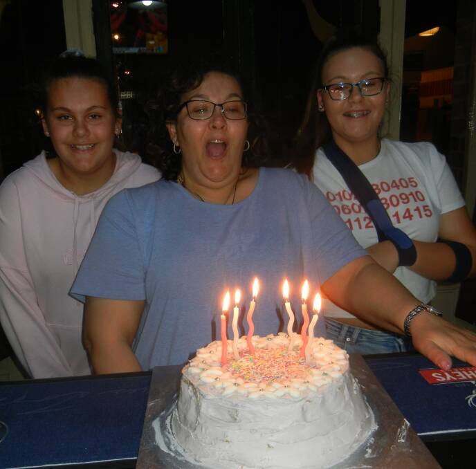 Margaret Gundry blowing out  the candles on her 50th birthday cake with her daughters  Regan and Hannah.  