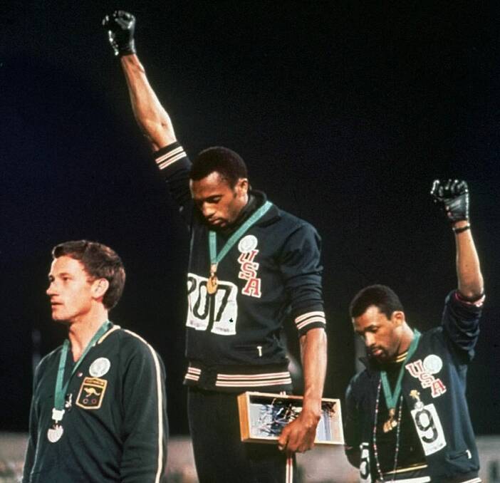 In this Oct. 16, 1968, file photo, U.S. athletes Tommie Smith, center, and John Carlos stare downward and extend gloved hands skyward in a Black power salute after Smith received the gold and Carlos the bronze for the 200 meter run at the Summer Olympic Games in Mexico City. Australian silver medalist Peter Norman is at left. Tommie Smith and John Carlos are part of the 2019 U.S. Olympic and Paralympic Hall of Fame class. (AP Photo)