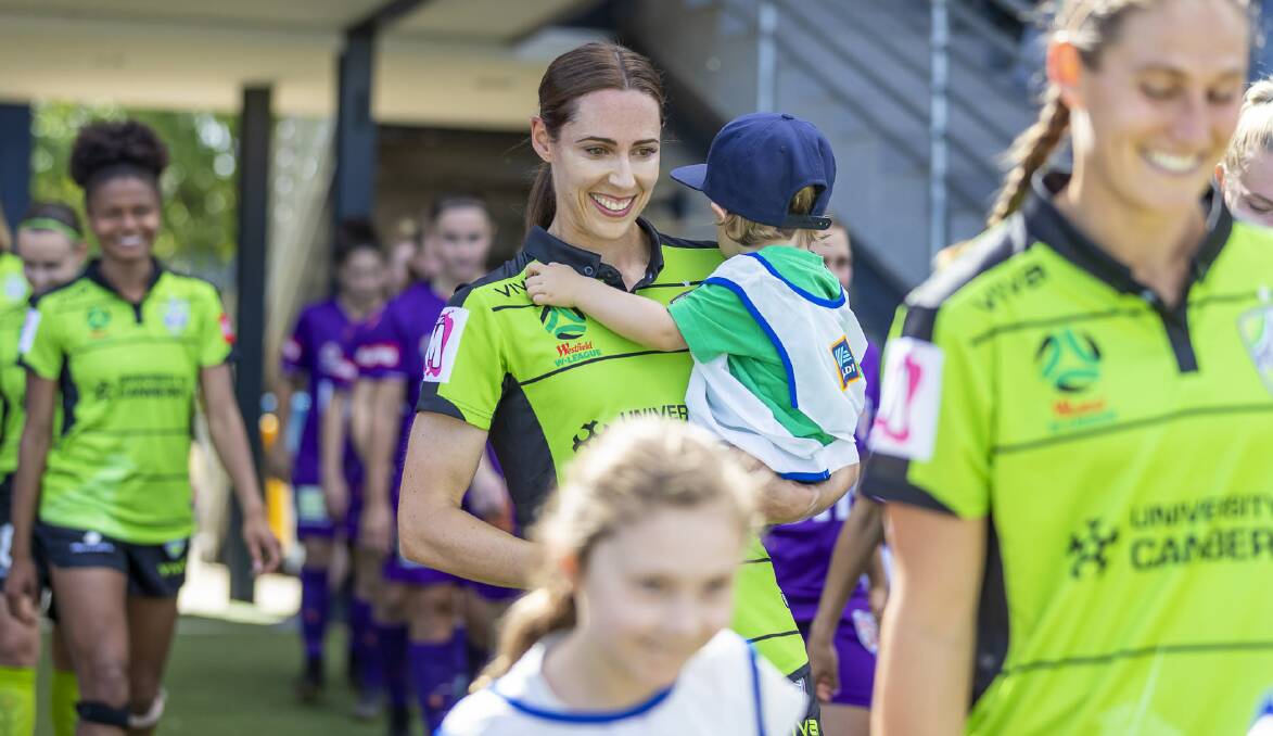 Canberra United defender Jessie Rasschaert carries her son Tristan onto the field before her W-League debut. Picture: Michael Daniel Photography
